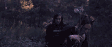 a blurry picture of two people in a dark forest with trees in the background