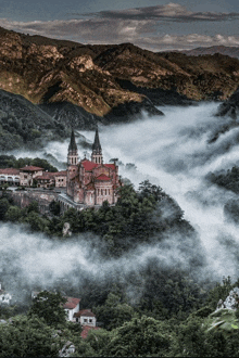 a church is surrounded by fog and mountains