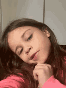 a little girl in a pink shirt is looking at the camera