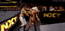 two women wrestling in front of an nxt banner