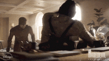 a poster for daredevil shows two men standing around a table