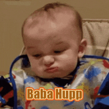 a baby wearing a bib is making a funny face and says baba hupp