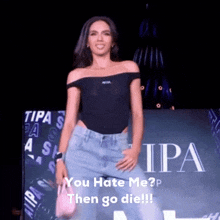 a woman in a black off the shoulder top is standing on a stage