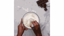 a person is whisking a bowl of whipped cream .