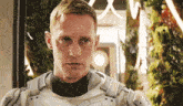 a man in a white armored suit looks at the camera