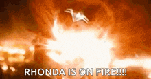 a person is standing in front of a large explosion with the words `` rhonda is on fire ! ''