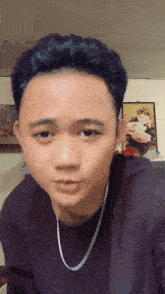 a young man wearing a black shirt and a silver chain around his neck