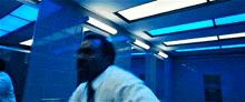 a man in a white shirt and tie is standing in a dark room with blue lights
