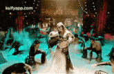 a woman is dancing on a stage with a group of people behind her .