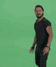a man in a black shirt is dancing in front of a green screen with the words just written on it .