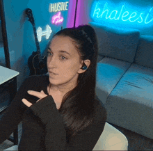 a woman sitting in front of a neon sign that says khaleesi
