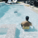 a man is sitting in a swimming pool looking out