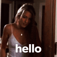 a woman in a white tank top is standing in a doorway and says hello