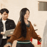 a woman in a brown sweater is holding a laptop with a sticker that says lg
