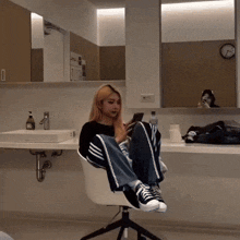 a woman is sitting in a chair looking at her phone