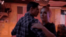 a man and a woman are dancing in front of an american flag .