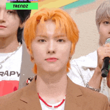 a man with orange hair is wearing a brown suit and a red necklace