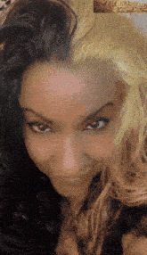 a close up of a woman 's face with half black and half yellow hair