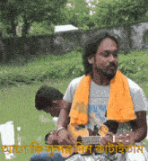 a man with an orange scarf around his neck playing a guitar