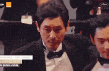 a man in a tuxedo is standing next to another man in a tuxedo at a red carpet