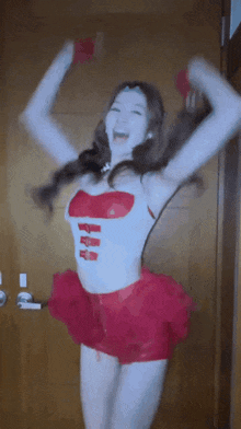 a woman in a white top and red skirt is dancing with her arms in the air
