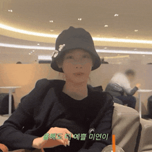 a woman wearing a black hat is sitting in a chair with a cup of orange juice