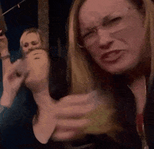 a woman wearing glasses is making a funny face while sitting in a crowd of people .