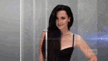 a woman in a black dress is standing in front of a glass door .