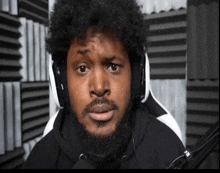 a man with a beard wearing headphones and a black shirt with the letter b on it