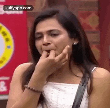 a woman is biting her nails while wearing a white top .