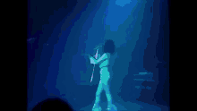 a woman singing into a microphone while standing on a stage