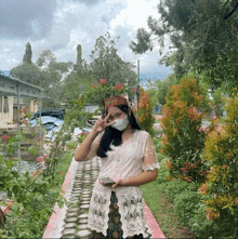 a woman wearing a face mask is standing in a park