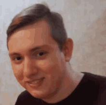 a close up of a man 's face with a blurred background . he is smiling and looking at the camera .