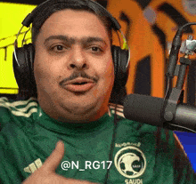 a man wearing headphones and a green saudi shirt