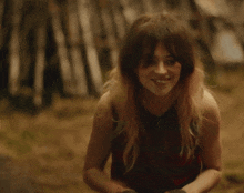 a woman blowing a kiss in a forest with her hands on her face