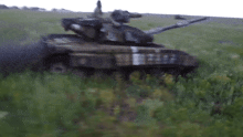 a military tank is driving through a grassy field with a smoke trail