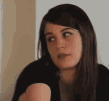 a woman in a black shirt is making a funny face while looking at the camera .