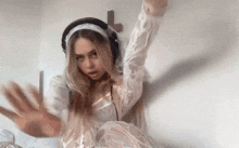 a woman in a white dress and headphones is dancing in front of a cross