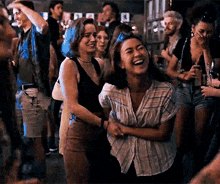 a group of people are standing in a crowd at a party and laughing .