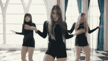 three women are dancing in front of a window in a room