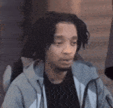 a man with dreadlocks and a beard is sitting in a chair with his eyes closed .