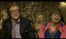 a man wearing glasses and a purple tie is sitting next to another man