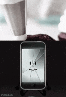 a cell phone with a cracked screen and a face on it .