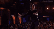 a man is dancing on a stage in front of a crowd .