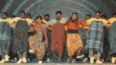 a group of people are dancing with plaid blankets around their waists