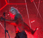 a woman with pink hair is standing in front of a microphone on a stage .