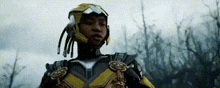 a man in a superhero costume is standing in a field wearing a helmet .