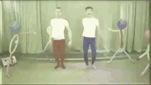 two men are dancing in a room with balloons and a sign that says " raz-dwa "