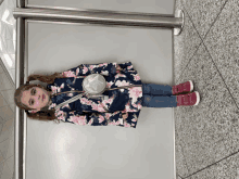 a little girl wearing a floral coat and a purse