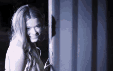 a woman is smiling while standing in a doorway in the dark .
